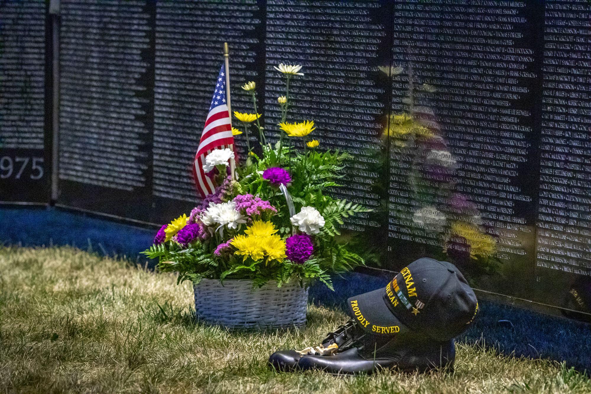 Flowers, boots, and a Vietnam veteran cap left at the base of The Wall