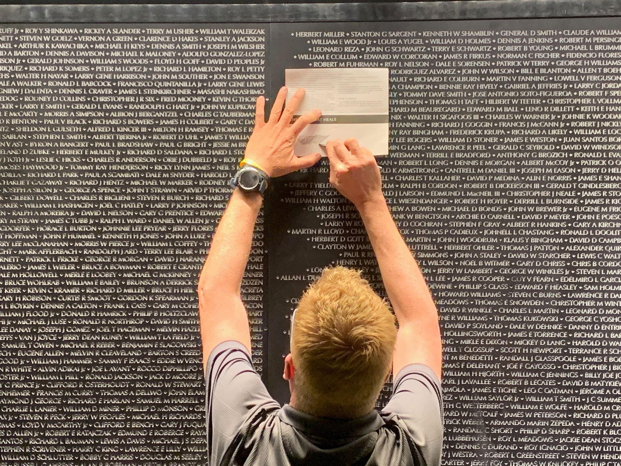 A visitor makes a pencil rubbing of a name at night
